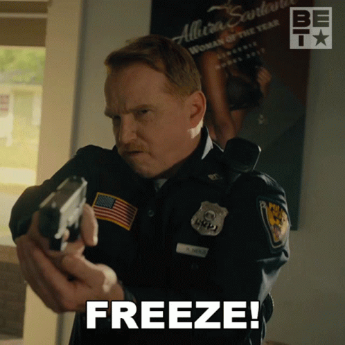 A Man In A Police Uniform Holding A Gun With The Word Freeze Above Him GIF