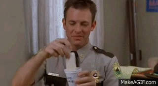 A Man In A Police Uniform Is Holding A Cup Of Ice Cream In His Hand . GIF