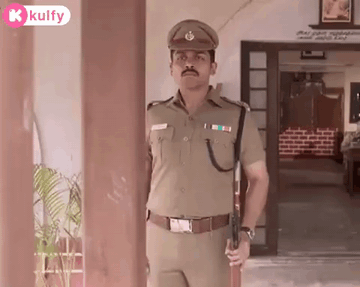 A Man In A Police Uniform Is Holding A Gun In Front Of A Doorway . GIF