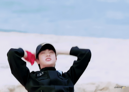 A Man In A Police Uniform Is Laying In The Sand With His Arms Outstretched .. GIF
