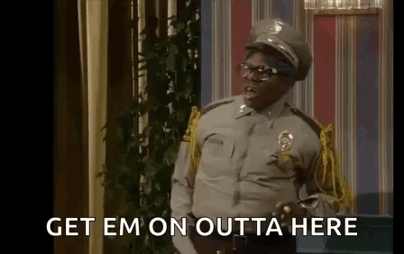 A Man In A Police Uniform Is Standing In A Room With The Words `` Get Em On Outta Here '' Written On The Screen . GIF
