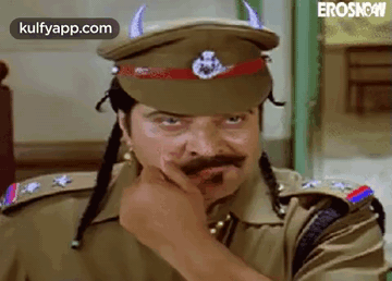 A Man In A Police Uniform Is Wearing A Hat With Horns On It And A Mustache . GIF