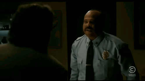 A Man In A Police Uniform Says " I 'Ll Take It " In A Dark Room GIF