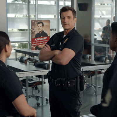 A Man In A Police Uniform Stands In Front Of A Poster That Says John Nolan GIF