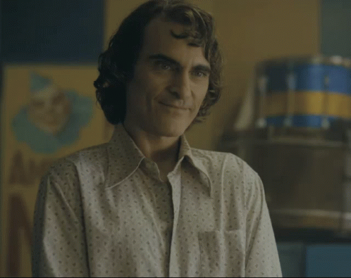 a man in a polka dot shirt is smiling in front of a sign that says ' a ' on it