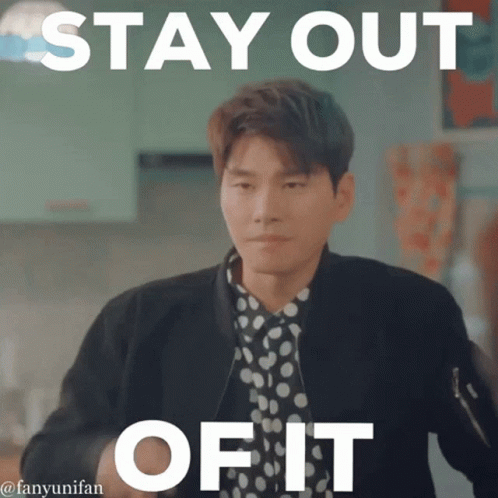 a man in a polka dot shirt is standing in front of a sign that says " stay out of it "