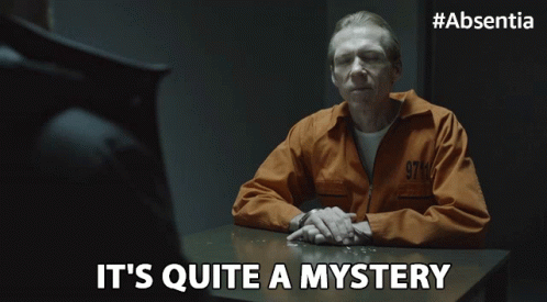 A Man In A Prison Uniform Sits At A Table With The Words It 'S Quite A Mystery Below Him GIF