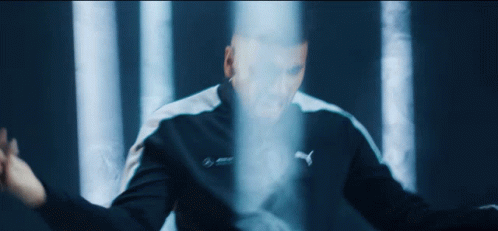 A Man In A Puma Jacket Stands In Front Of A Blue Light GIF