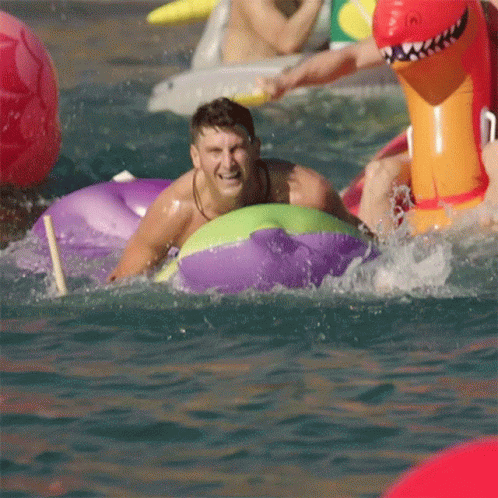 A Man In A Purple And Green Raft Is Splashing In The Water GIF