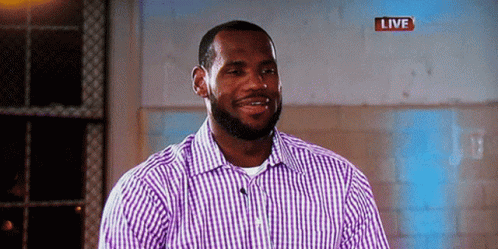 a man in a purple and white checkered shirt is smiling in front of a live sign