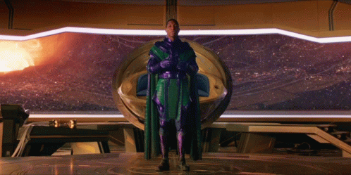 A Man In A Purple Cape Stands In Front Of A Large Window GIF