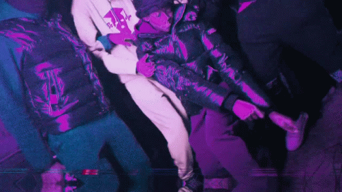 A Man In A Purple Jacket Is Holding Another Man GIF