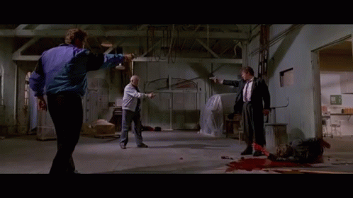 A Man In A Purple Jacket Is Pointing A Gun At Another Man GIF
