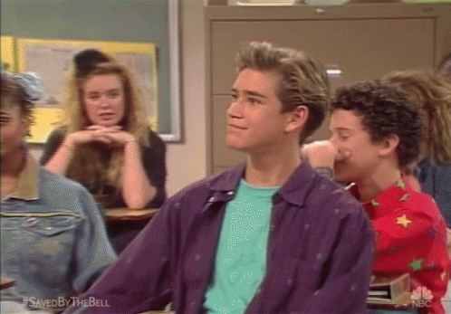 A Man In A Purple Jacket Is Sitting In A Classroom With Other Students GIF