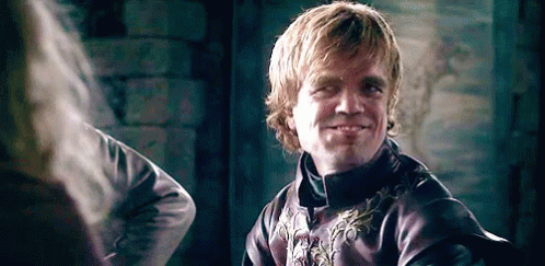 A Man In A Purple Jacket Is Smiling While Looking At Another Man . GIF
