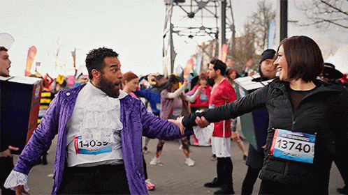 A Man In A Purple Jacket With The Number 1 On His Shirt Shakes Hands With A Woman GIF