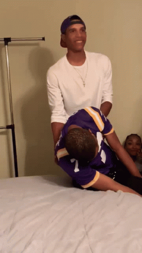 A Man In A Purple Jersey With The Number 7 On It Is Laying On Another Man 'S Back GIF