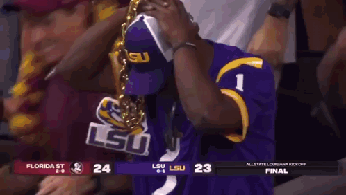 a man in a purple lsu jersey is wearing a gold chain around his neck ..