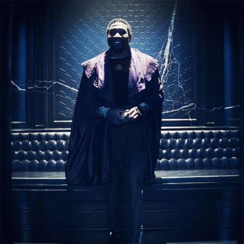 A Man In A Purple Robe Stands In Front Of A Blue Wall GIF