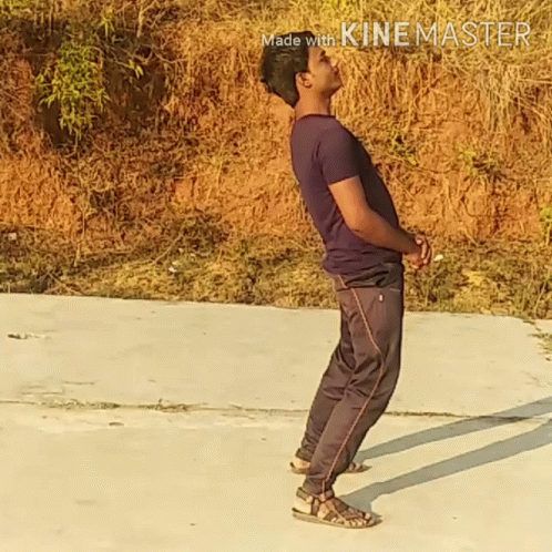 A Man In A Purple Shirt And Black Pants Is Standing On A Concrete Surface With The Words Made With Kinemaster In The Cor GIF