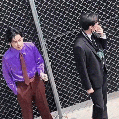 A Man In A Purple Shirt And Tie Is Standing Next To A Man In A Black Suit . GIF