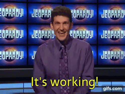 a man in a purple shirt and tie says it 's working on a jeopardy show .