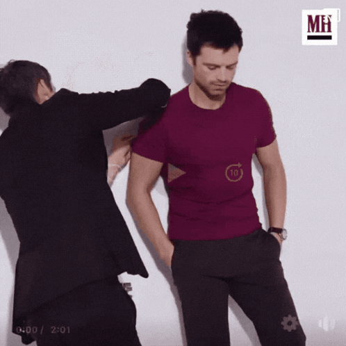 A Man In A Purple Shirt Is Being Touched By Another Man . GIF