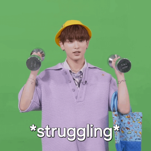 A Man In A Purple Shirt Is Holding A Dumbbell And A Blue Bag With The Words * Struggling * Written Below Him GIF