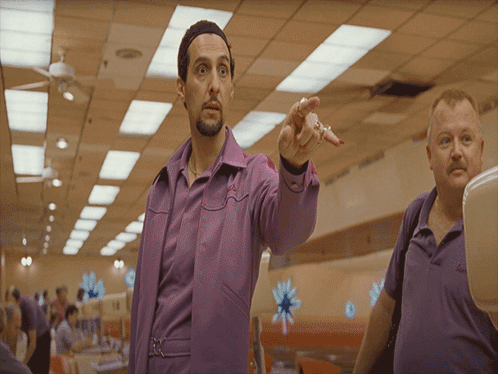 A Man In A Purple Shirt Is Pointing To Something GIF