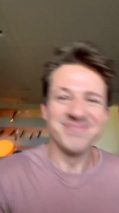 A Man In A Purple Shirt Is Smiling And Making A Funny Face GIF