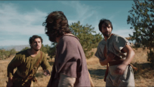 A Man In A Purple Shirt Is Standing In A Field With Other Men GIF
