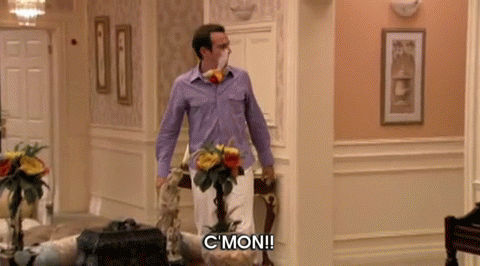 A Man In A Purple Shirt Is Standing In A Hallway And Says " C Mon " GIF