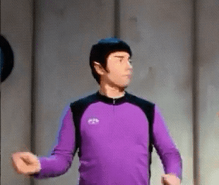 A Man In A Purple Shirt Is Standing In A Room With His Arms Outstretched GIF