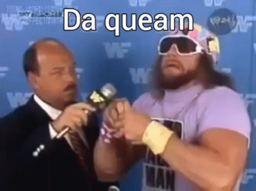 A Man In A Purple Shirt Is Talking Into A Microphone With A Man In A Suit Behind Him . GIF