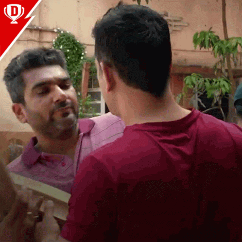 A Man In A Purple Shirt Is Talking To Another Man GIF