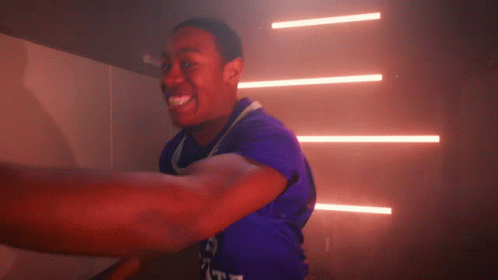 A Man In A Purple Shirt With The Word Duke On The Front GIF