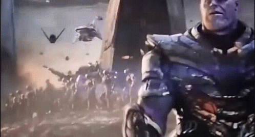 A Man In A Purple Suit Is Standing In Front Of A Crowd Of People With Planes Flying In The Background GIF