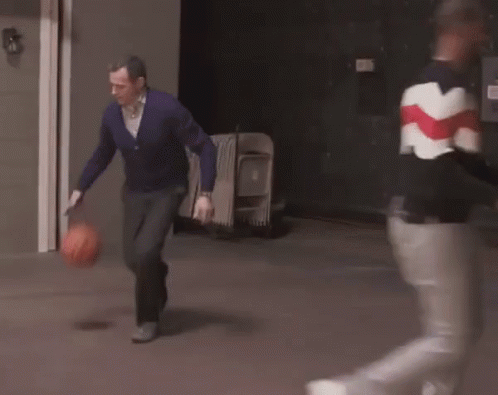A Man In A Purple Sweater Is Running With A Basketball In His Hands . GIF