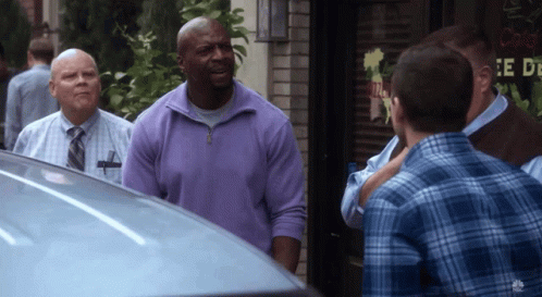 A Man In A Purple Sweater Is Standing In Front Of A Sign That Says " E De " GIF