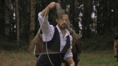 A Man In A Purple Vest Is Lassoing A Small Black Calf GIF