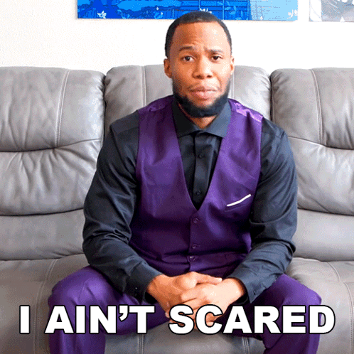 A Man In A Purple Vest Is Sitting On A Couch With The Words I Ain 'T Scared GIF