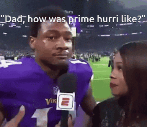 A Man In A Purple Vikings Jersey Is Being Interviewed By A Woman . GIF
