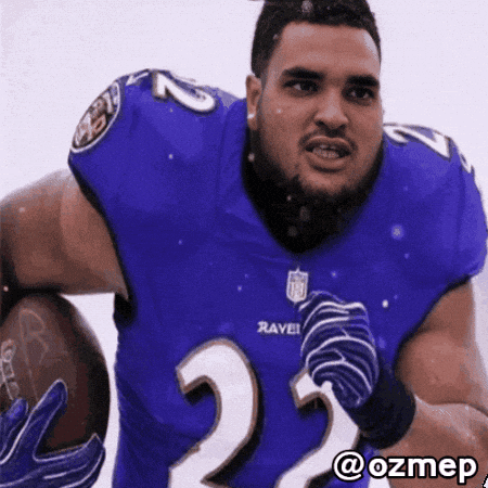a man in a ravens jersey holds a football in his hands