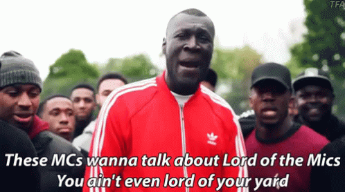 A Man In A Red Adidas Jacket Stands In Front Of A Crowd Of People GIF