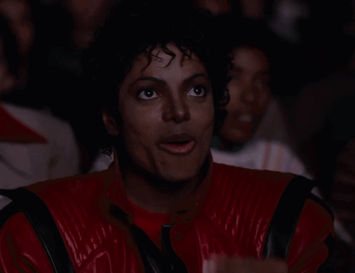 A Man In A Red And Black Jacket Is Eating Popcorn GIF