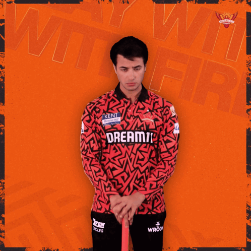 A Man In A Red And Black Shirt Holds A Ton Cricket Bat GIF
