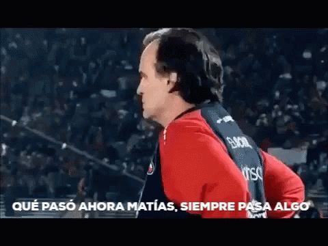 A Man In A Red And Black Shirt Is Standing In Front Of A Crowd And Says Que Paso Ahora Matias Siempre Pasa Algo GIF