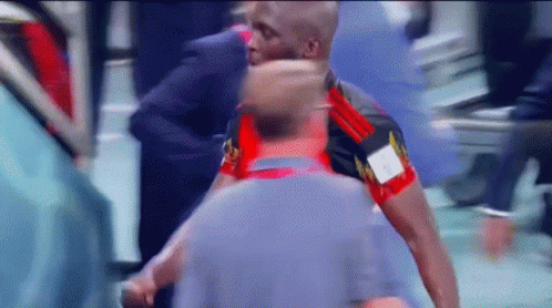 A Man In A Red And Black Shirt With The Letter A On It Is Standing Next To Another Man GIF