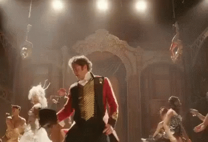 A Man In A Red And Gold Uniform Is Dancing On A Stage With A Group Of People . GIF