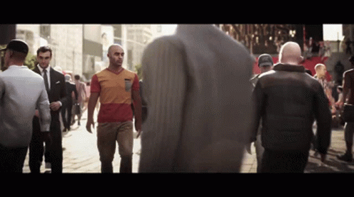 A Man In A Red And Orange Shirt Walks Down A Street With Other People GIF